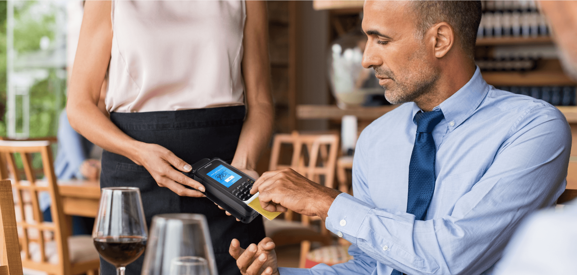 レストランでmPOS ハンドヘルドケースを使用して支払いを済ませる男性。